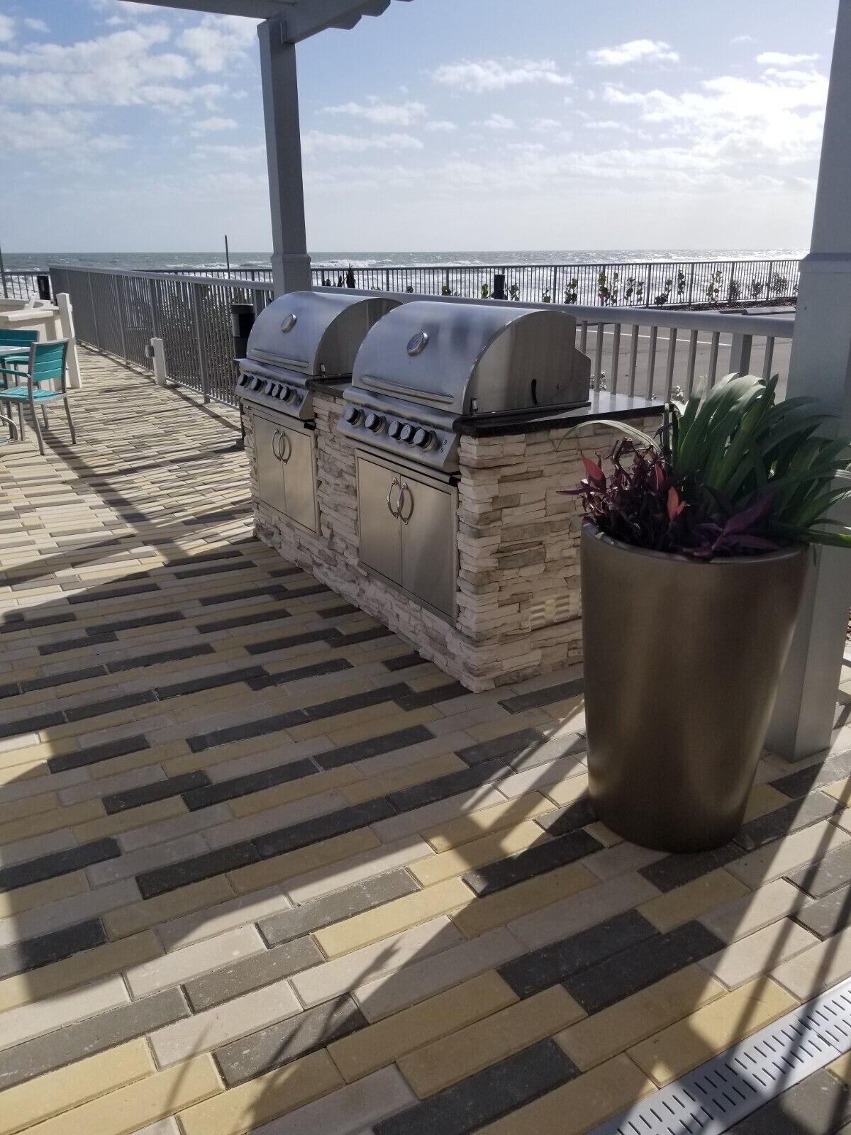 A patio with a barbecue grill and a potted plant.