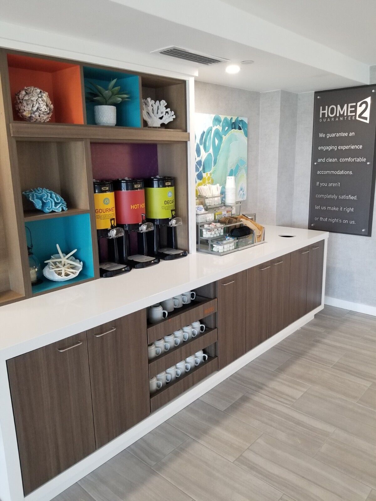 A modern kitchen area with a coffee station, decorative items, and a sign about a home guarantee.