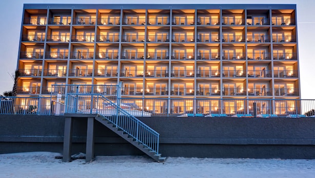 A multi-story hotel with balconies, a staircase, and a snow-covered ground.