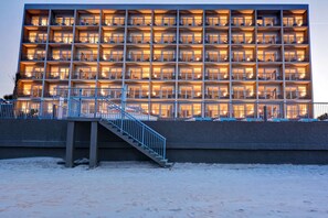 A multi-story hotel with balconies, a staircase, and a snow-covered ground.