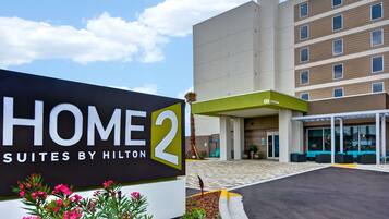 Entrada de hotel com uma placa indicando 'HOME 2 SUITES BY HILTON'.