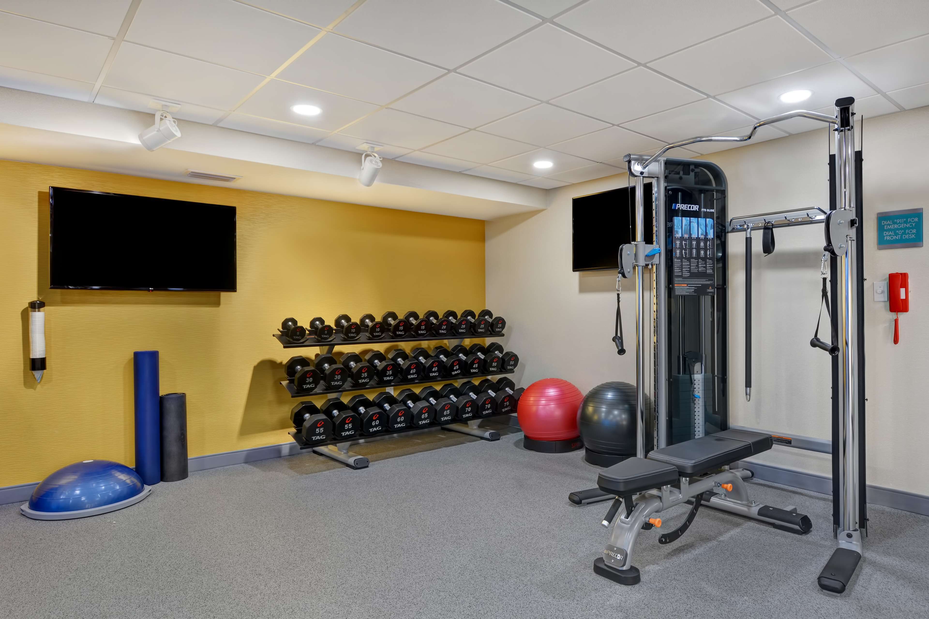 Un gimnasio con equipo de ejercicio, pesas y una pantalla de televisión.
