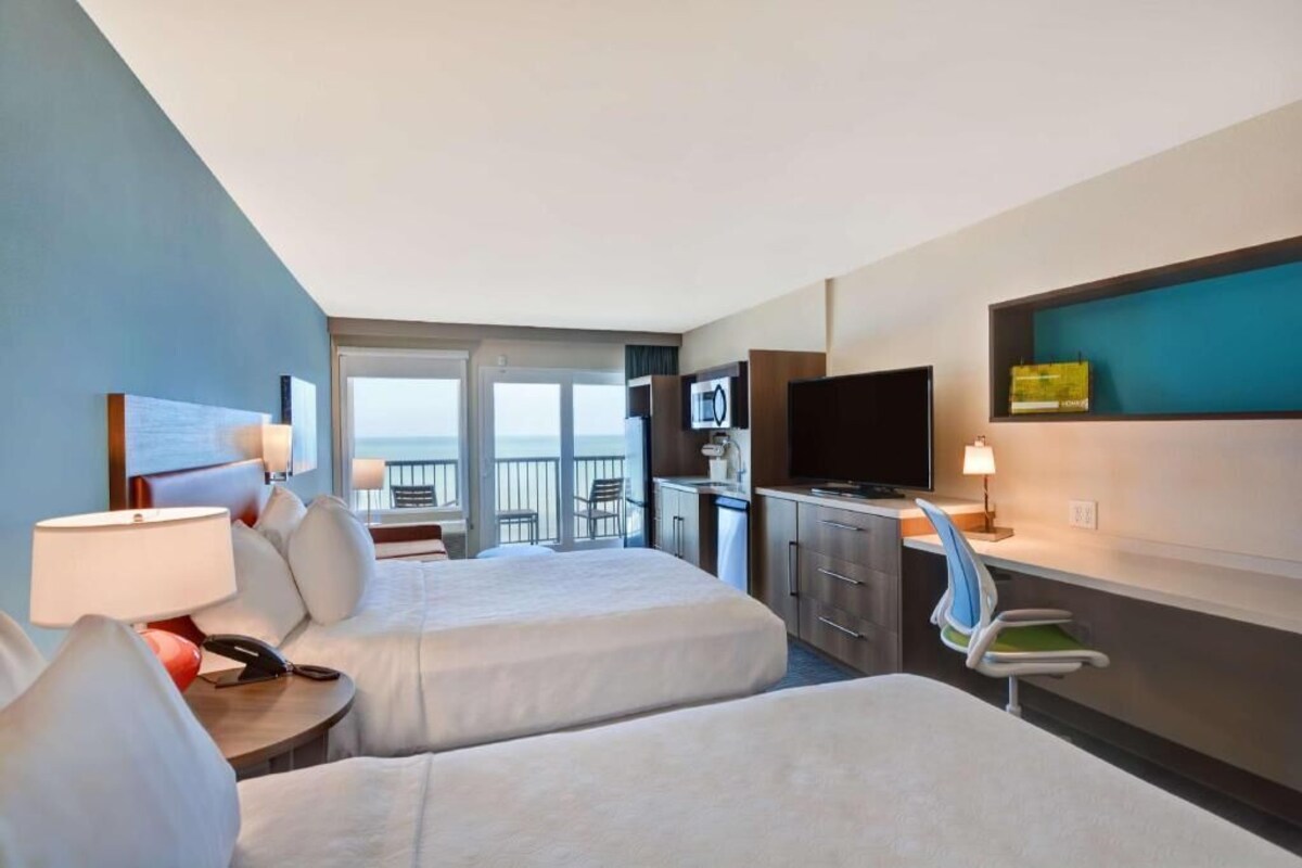 Une chambre d’hôtel avec deux lits, un bureau, une télévision et un balcon.