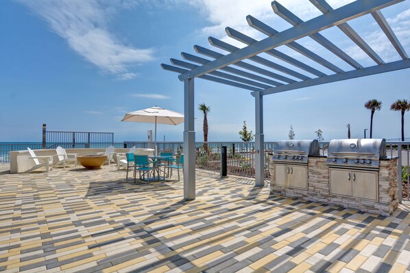 An outdoor patio with a grill, seating area, and a view of the ocean.
