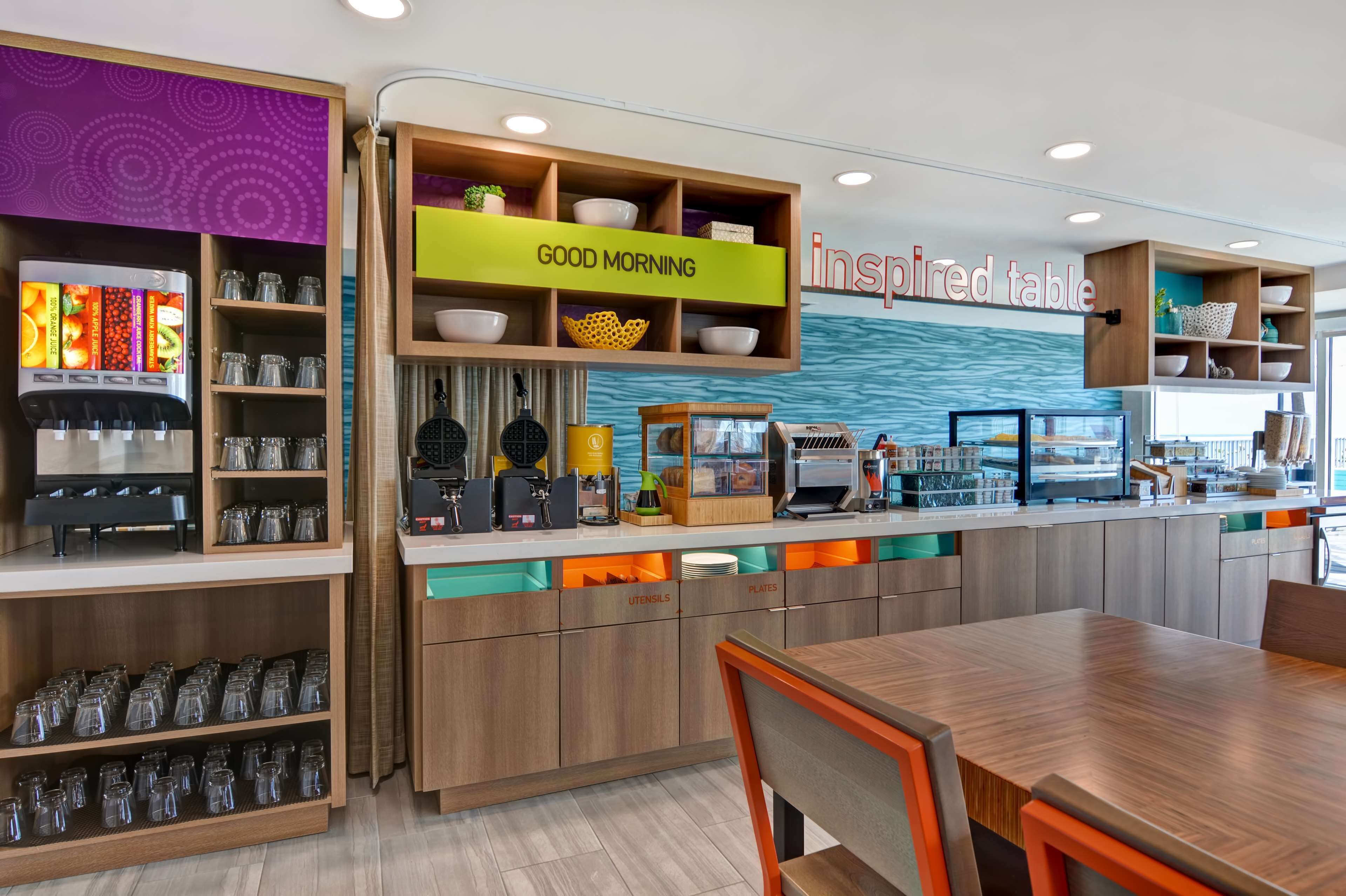 A modern cafe with a self-serve coffee station, a 'Good Morning' sign, and a 'Inspired Table' sign.