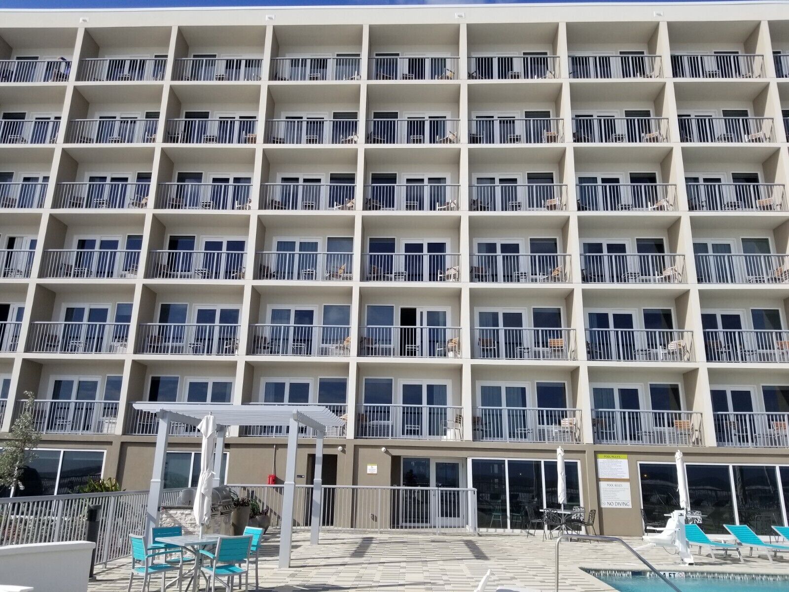 A multi-story hotel with balconies, outdoor seating, and a pool area.