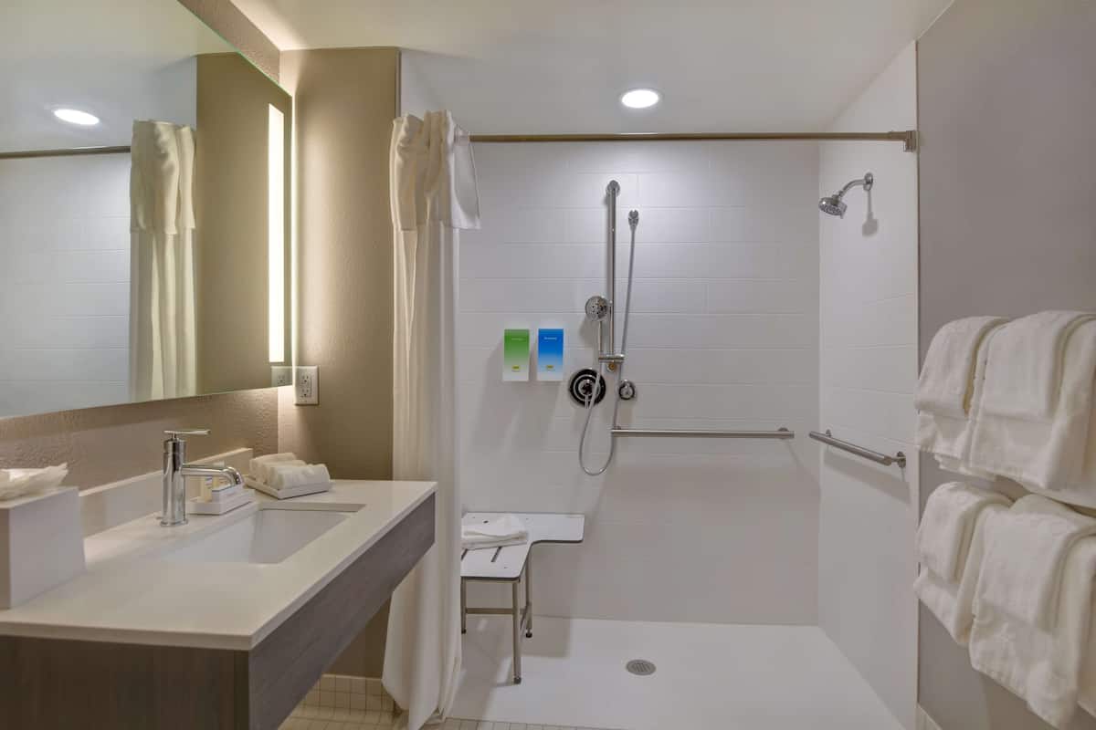 Une salle de bain moderne avec une douche à l’italienne, un lavabo avec un miroir et un porte-serviettes.