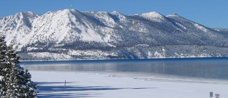 Un lac recouvert de neige, avec des montagnes en arrière-plan et un banc au premier plan.
