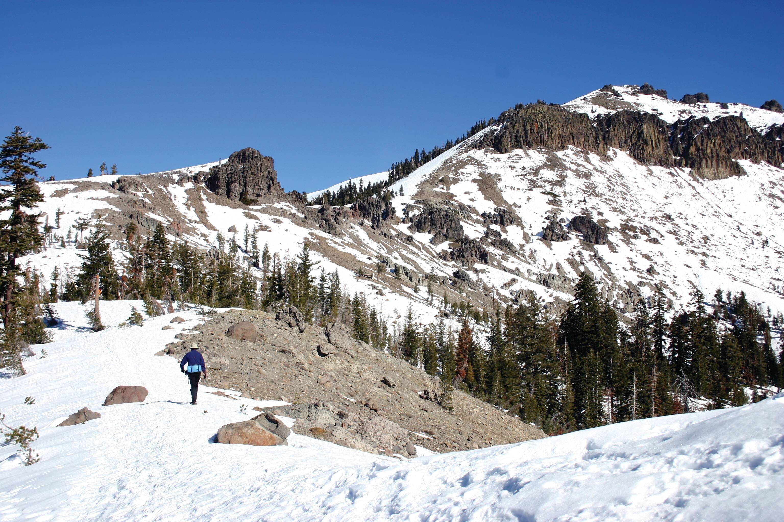 A snowy mountain landscape with a hiker in the foreground.