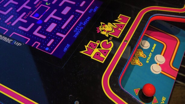 Gros plan sur une borne d’arcade de jeu vidéo, avec un jeu de labyrinthe et un personnage nommé « Mme PAC ».