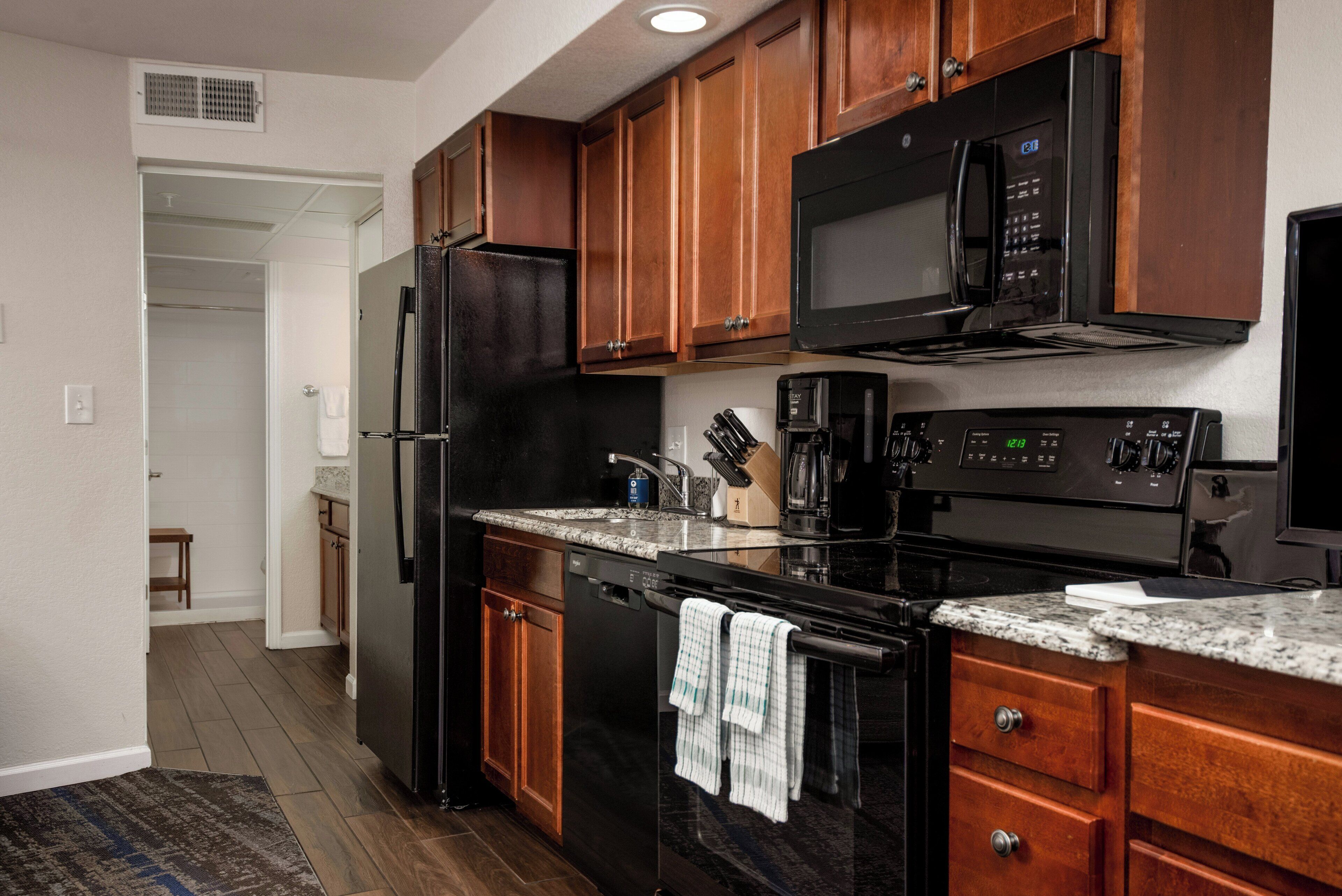 A kitchen with wooden cabinets, a black refrigerator, a microwave, a stove, and a dishwasher.