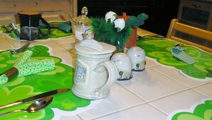 A table set with a mug, salt and pepper shakers, a knife, and a spoon on a green placemat.
