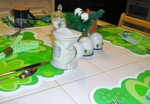 A table set with a mug, salt and pepper shakers, a knife, and a spoon on a green placemat.