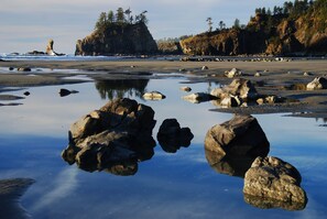 A rocky shoreline with large boulders and calm water reflecting the landscape.