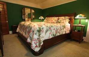 Une chambre à coucher avec une couvre-lit à motifs floraux, une tête de lit en bois, une table de chevet avec une lampe et un miroir au mur.