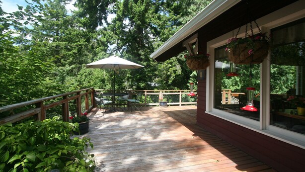 Une terrasse en bois avec une rambarde, des plantes en pot et des jardinières suspendues.
