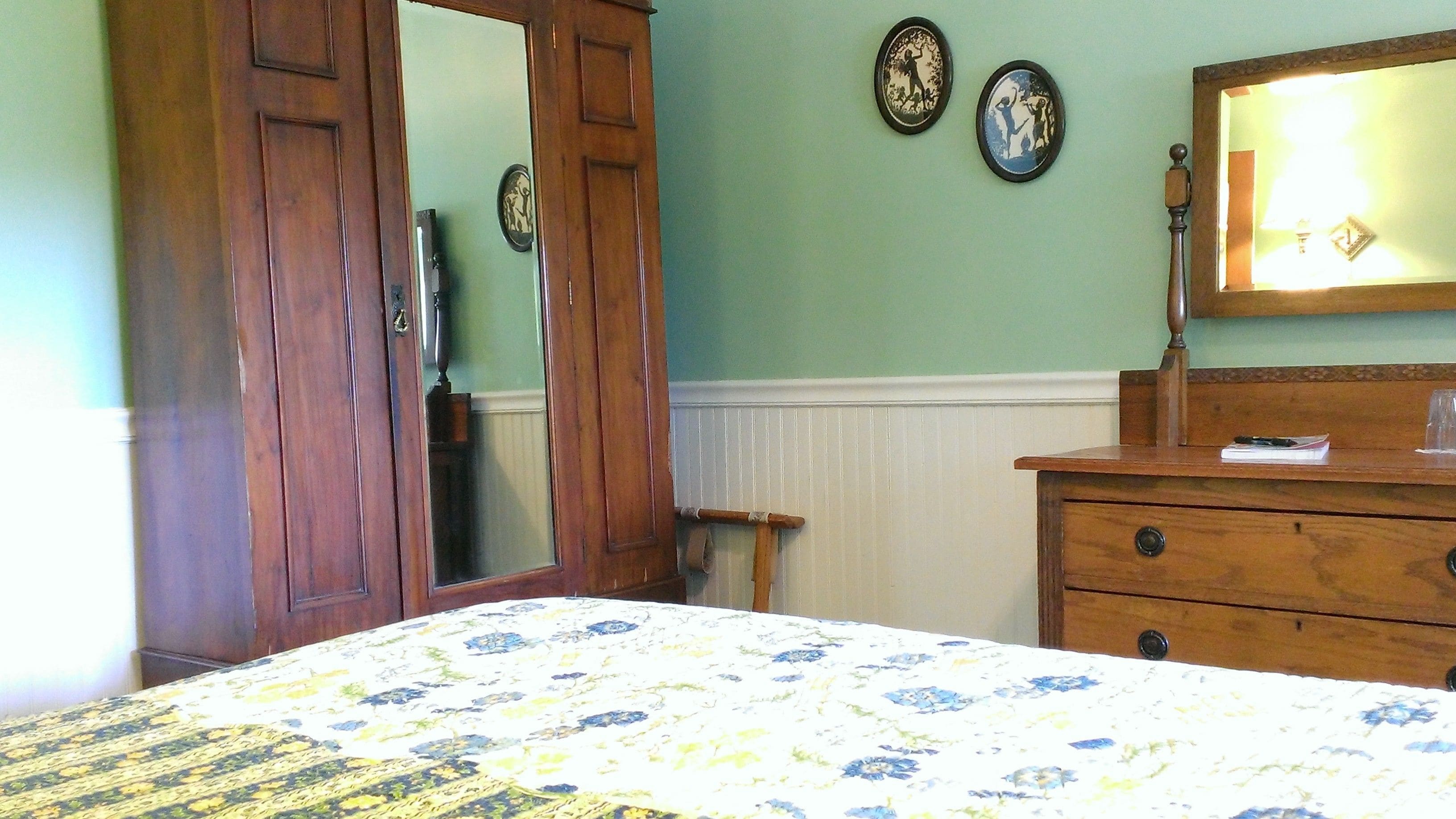 Une chambre à coucher avec un lit, une commode et un miroir. Il y a deux horloges murales et un radiateur.