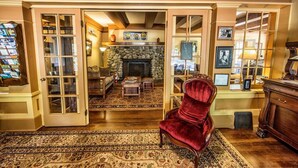Un salon chaleureux avec une cheminée, un fauteuil en velours rouge et un mur en pierre.