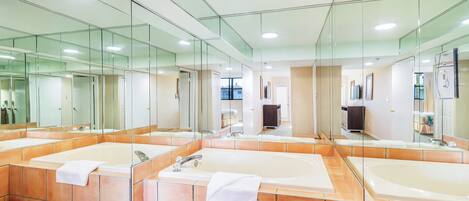 A modern bathroom with three large tubs, a glass shower enclosure, and a large mirror reflecting the space.