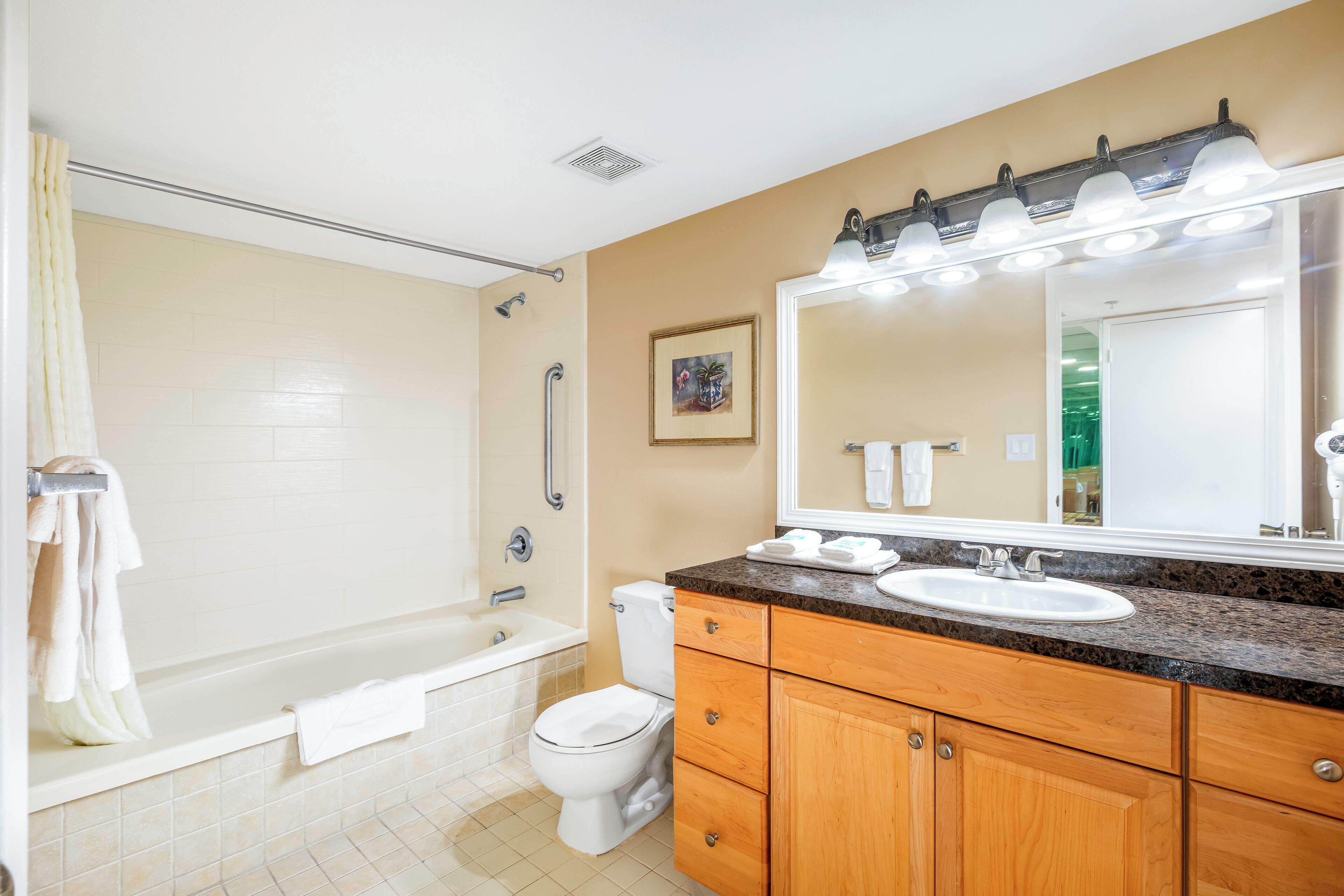 A bathroom with a bathtub, toilet, sink, and vanity.