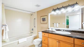 A bathroom with a bathtub, toilet, sink, and vanity.
