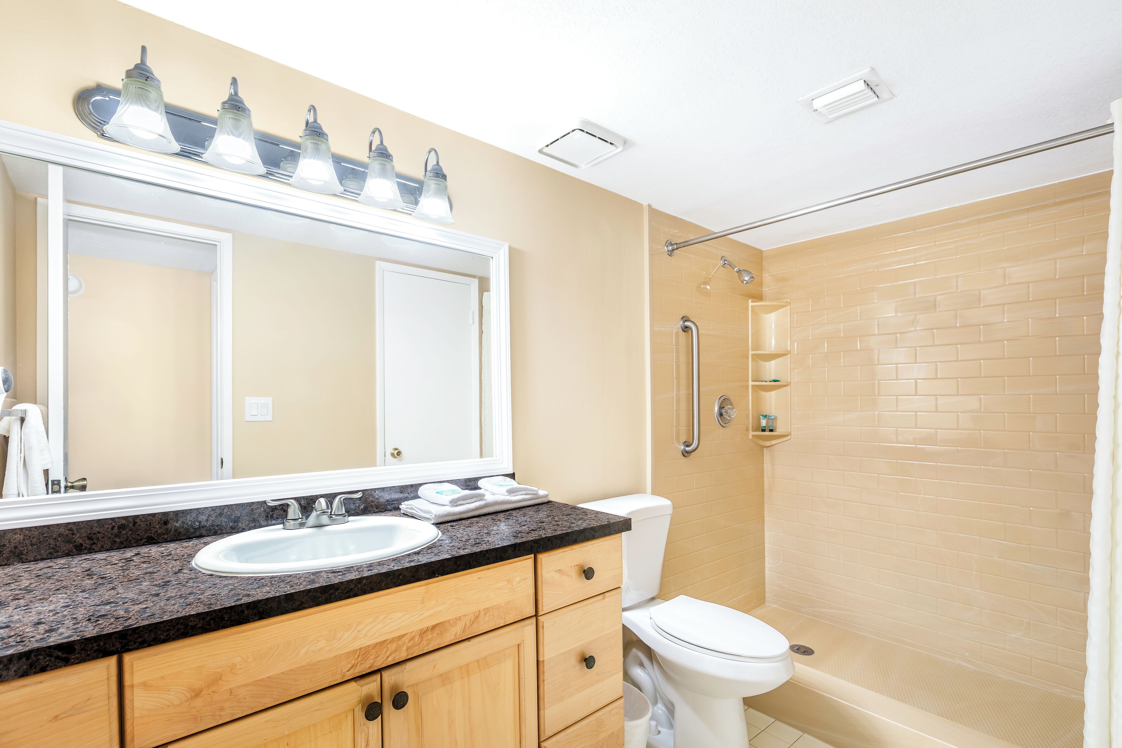 Une salle de bain équipée d’un lavabo, d’un miroir, de toilettes et d’une douche.