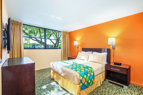 Habitación de hotel con cama, lámparas de noche, mesita de noche, escritorio y ventana con cortinas.