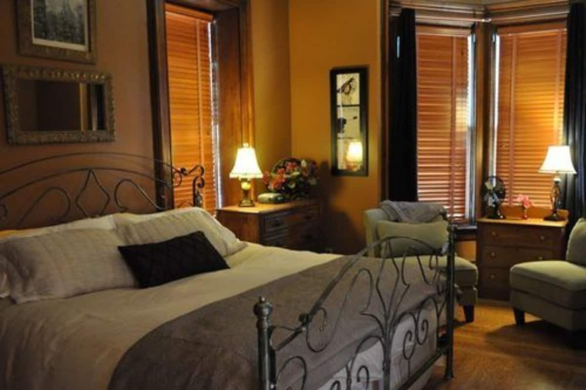 A hotel room with a large bed, a chair, a nightstand, and a dresser.