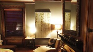 A hotel room with a bed, a chair, a desk, a lamp, and a large mirror.