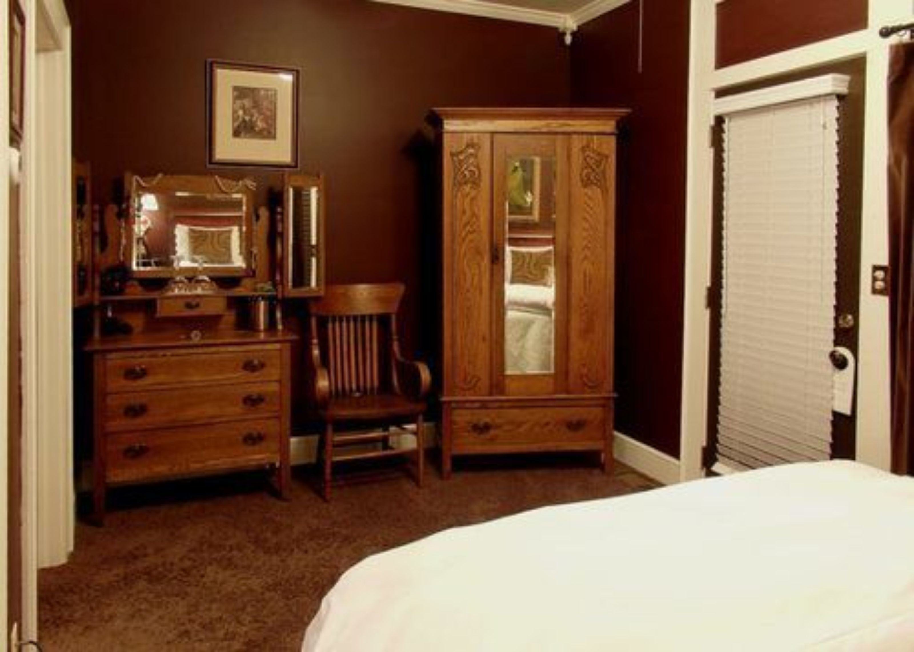 Un dormitorio con un aparador de madera, una silla y una cama.
