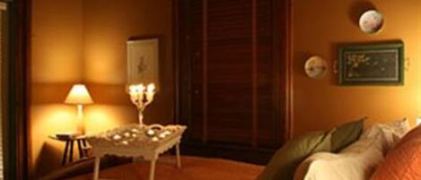 A hotel room with a bed, a bedside table with a lamp, and a wall clock.