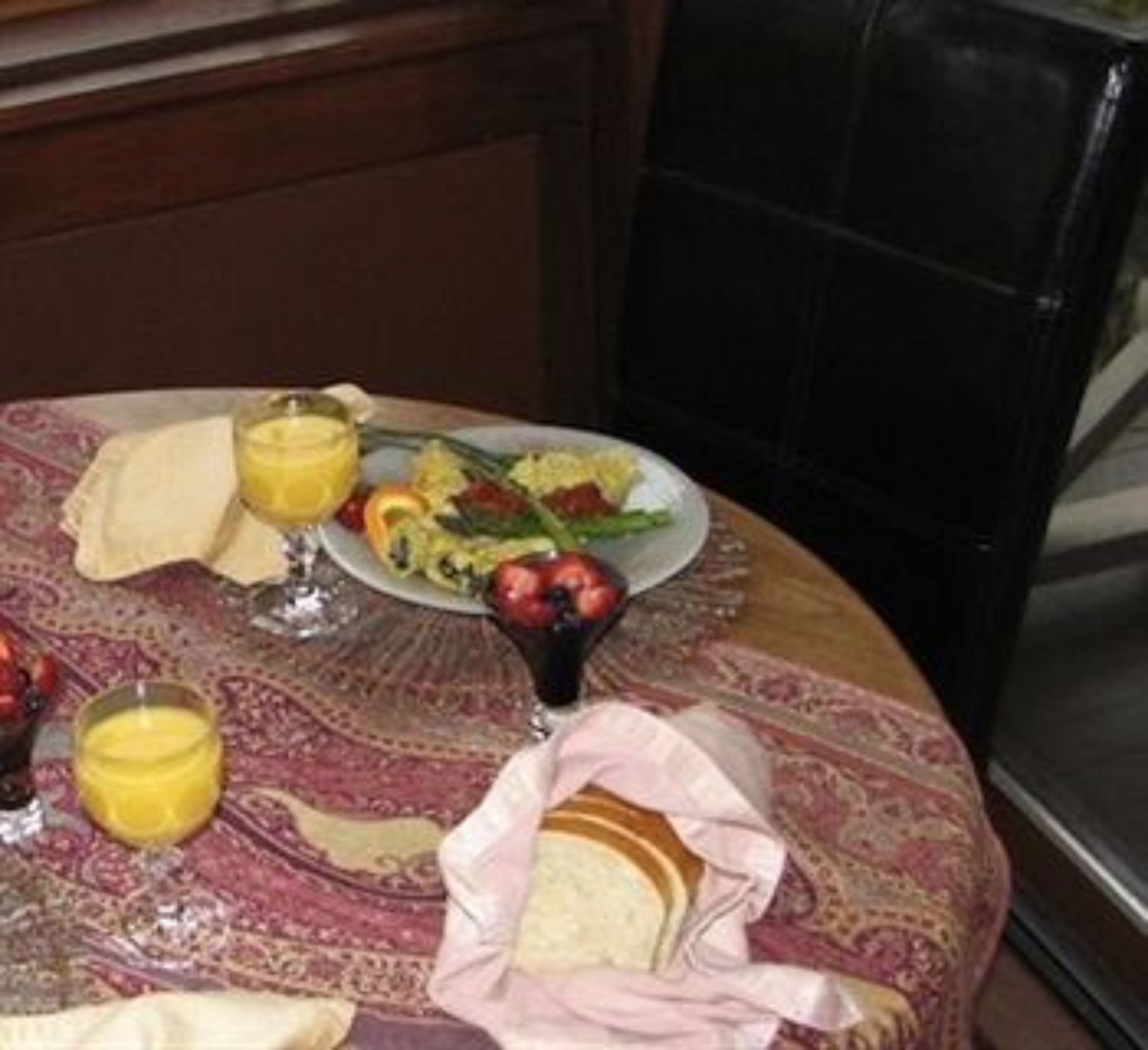 A dining table with a plate of food, a glass of orange juice, and a napkin.