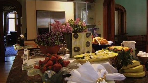 A breakfast buffet with various fruits, pastries, and a flower centerpiece.