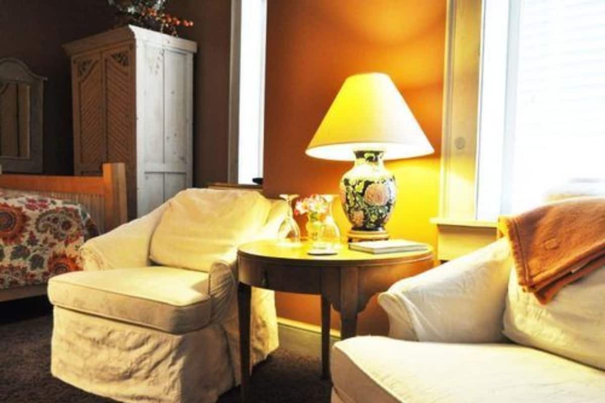 A cozy room with a sofa, a small table with a lamp, and a cabinet.