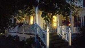 A grand staircase with white balustrades leading to a porch with a light fixture. - Pecan Tree Inn (Beaufort)