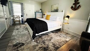 A bedroom with a bed, bedside table, lamp, and a decorative anchor on the wall. - Pecan Tree Inn (Beaufort)