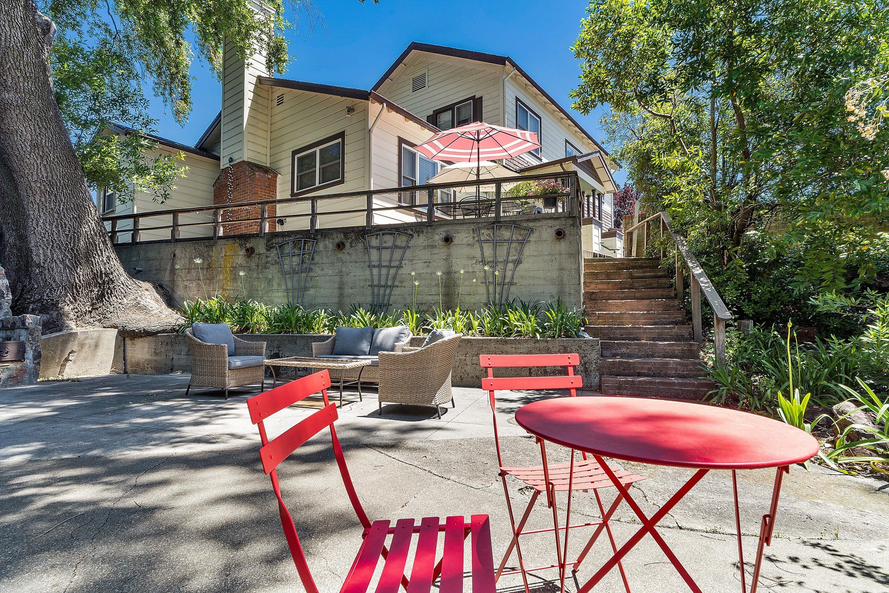 A house with a patio area featuring outdoor furniture and a red table.