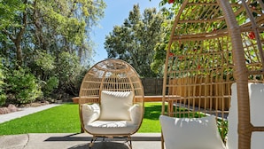 A wicker chair with cushions in a garden setting.