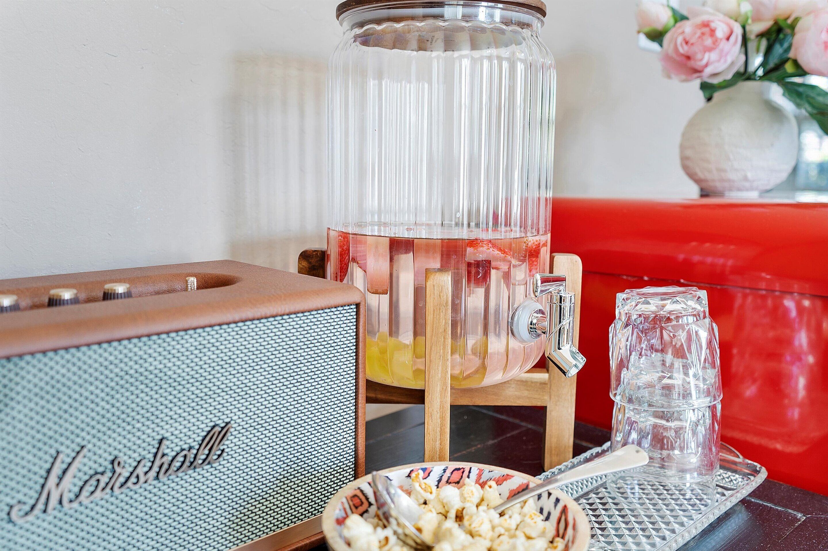 Un bol de ponche con fruta y un altavoz vintage Marshall, un cuenco de palomitas de maíz y un vaso sobre una bandeja.