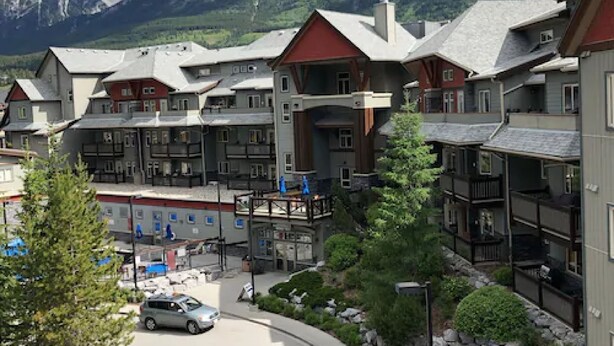 Un hotel de varios pisos con un telesilla, rodeado de montañas y árboles.