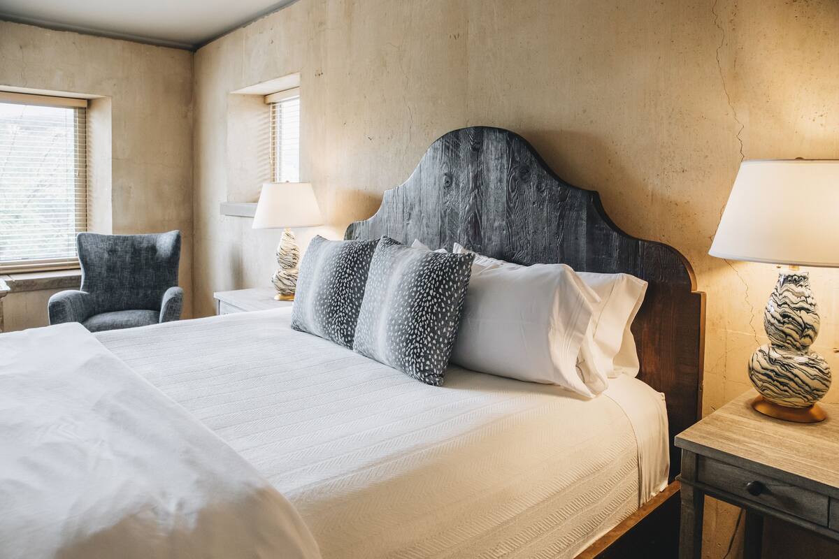 A hotel room with a large bed, two bedside tables, a chair, and a window.