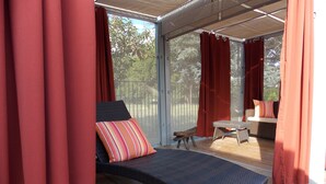 A covered outdoor seating area with a wicker lounge chair, a small table, and a bench. - Casa Bella (Kenwood)