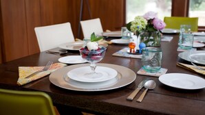 A dining table set with plates, cutlery, and a dessert bowl with berries and a mint leaf. - Casa Bella (Kenwood)