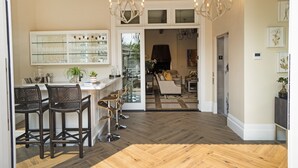 A spacious kitchen with a dining area, wooden flooring, and a chandelier. - The McClelland House (Napa)
