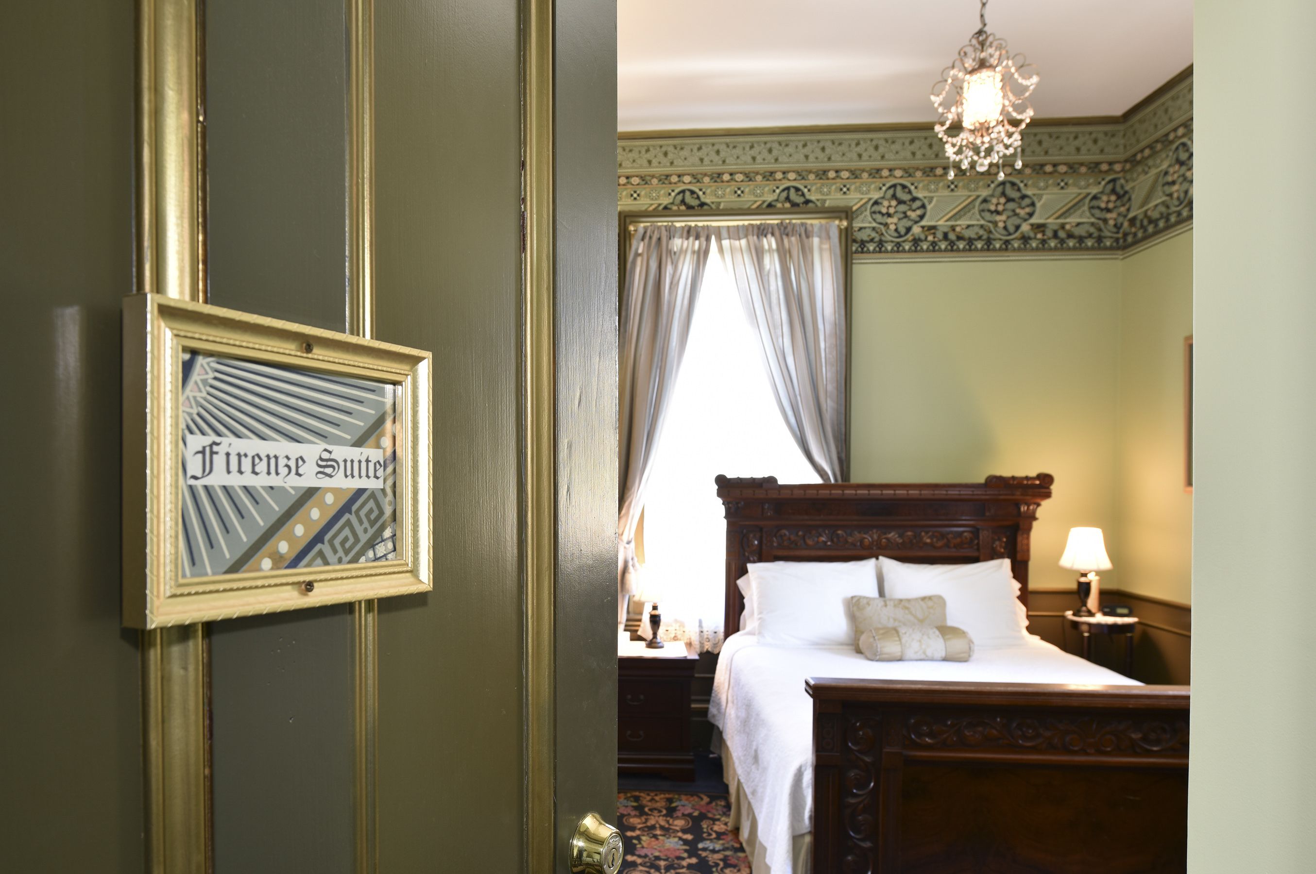 A bedroom with a bed, a nightstand, a lamp, and a chandelier.