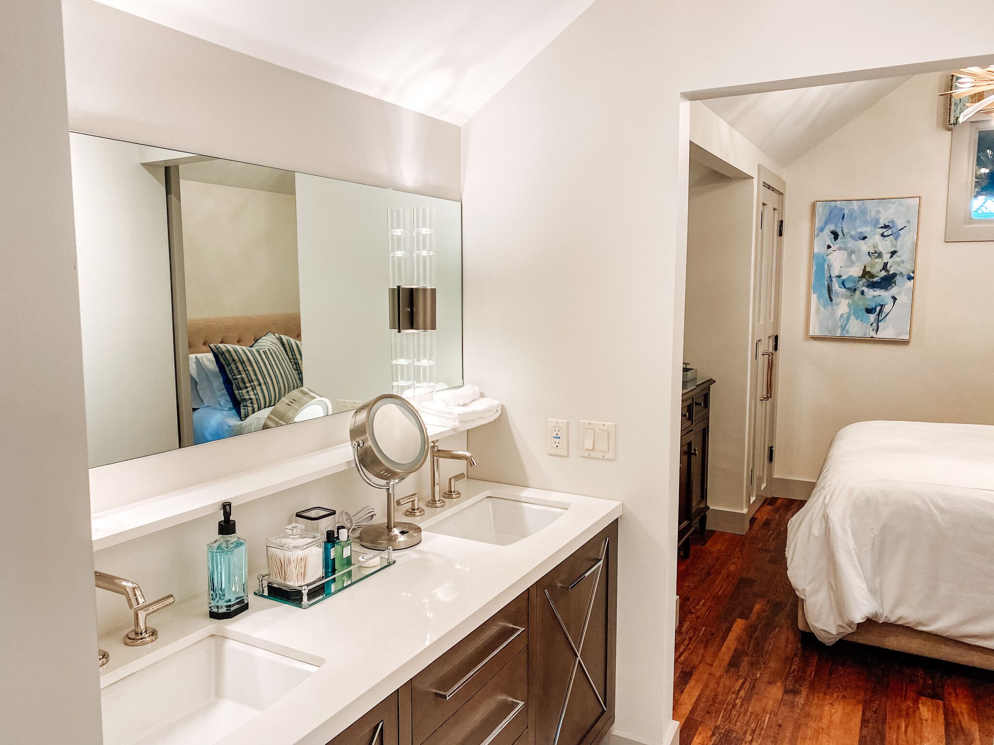A modern bathroom with a large mirror, two sinks, and a vanity with storage.