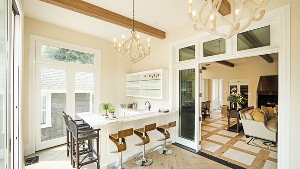 A spacious kitchen with a central island, bar stools, and a chandelier. - The McClelland House (Napa)