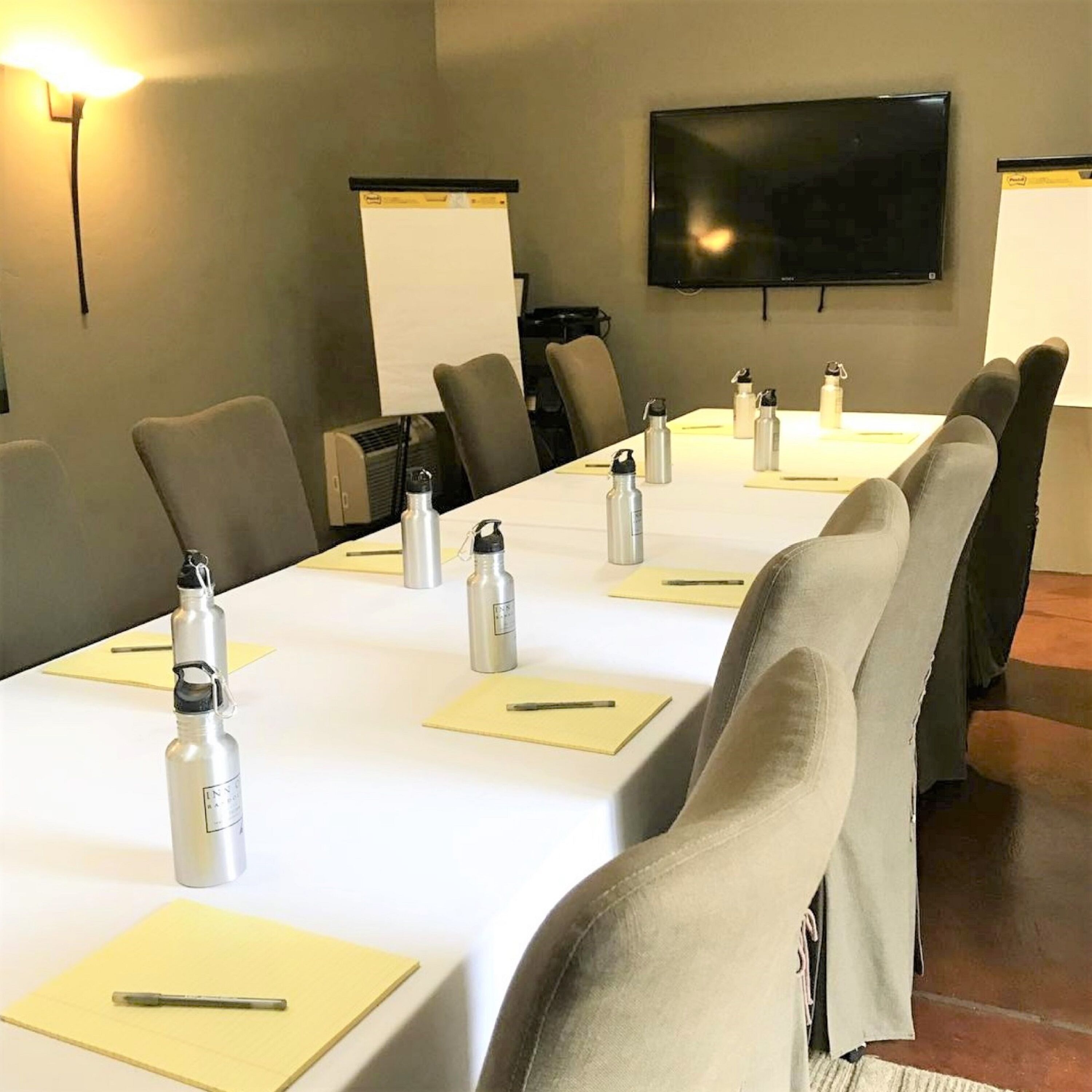 A conference room with a long table, chairs, water bottles, pens, and a whiteboard.