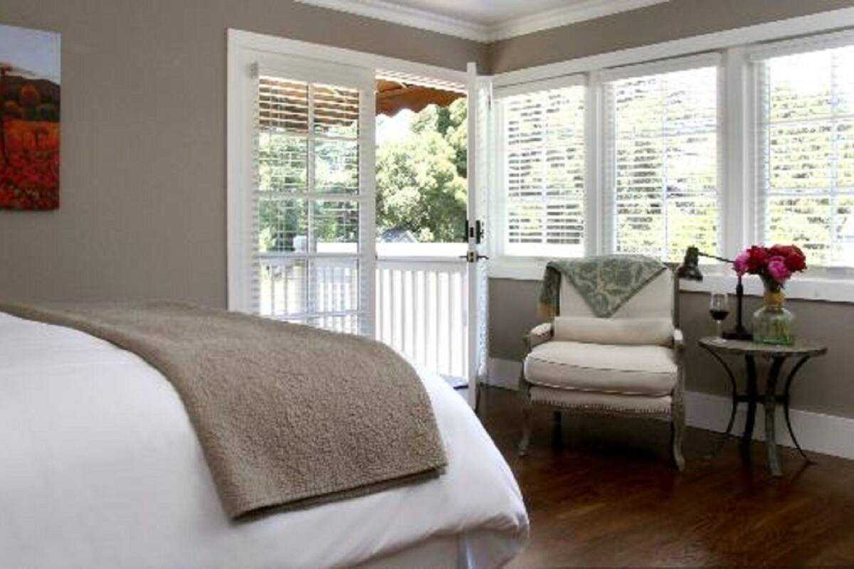 A bedroom with a large bed, a chair, and a table with flowers.