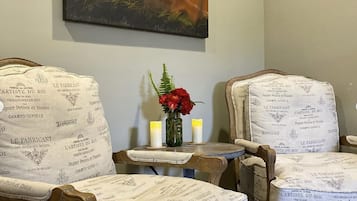 Relax in a stylish space with a large abstract art piece, comfortable seating, and a small table with a vase and candles.